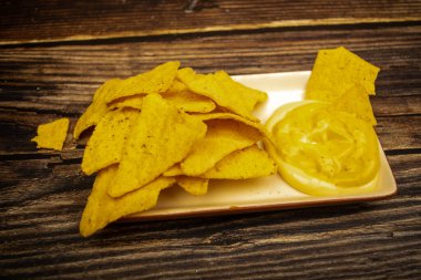 Tahta arka planda peynir soslu mısır cipsi. Kapat.