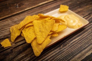 Tahta arka planda peynir soslu mısır cipsi. Kapat.