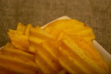 Tahta arka planda peynir soslu patates cipsi. Kapat.