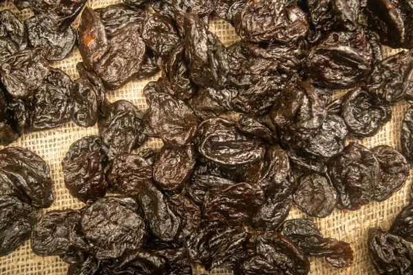 Dried prunes in bulk on burlap with a rough texture. Close up