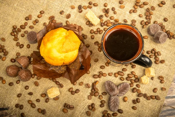 Frischer Cupcake Kaffeebecher Pralinen Und Kaffeebohnen Auf Einem Selbstgesponnenen Stoff — Stockfoto