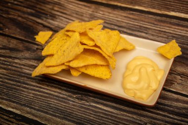 Tahta arka planda peynir soslu mısır cipsi. Kapat.