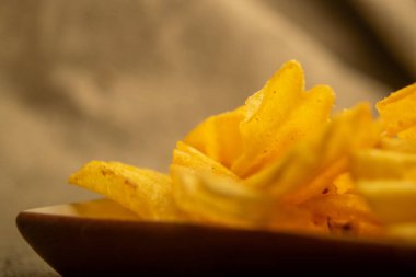 Tahta arka planda peynir soslu patates cipsi. Kapat.