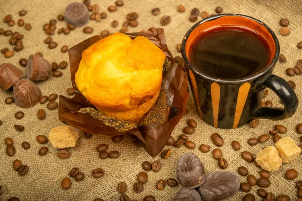 Frischer Cupcake Kaffeebecher Pralinen Und Kaffeebohnen Auf Einem Selbstgesponnenen Stoff — Stockfoto