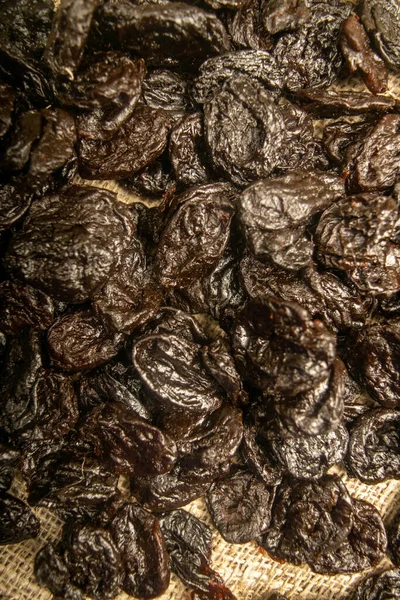 Dried prunes in bulk on burlap with a rough texture. Close up