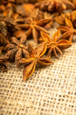 Çuval bezinin arka planında kabataslak desenli bir yıldız anason yığını. Kapat.