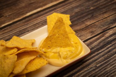 Tahta arka planda peynir soslu mısır cipsi. Kapat.