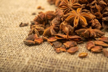 Çuval bezinin arka planında kabataslak desenli bir yıldız anason yığını. Kapat.