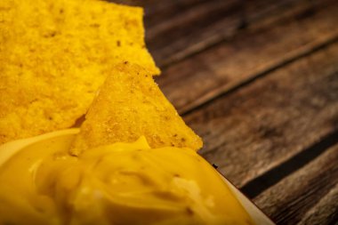 Tahta arka planda peynir soslu mısır cipsi. Kapat.