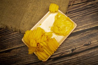 Tahta arka planda peynir soslu patates cipsi. Kapat.