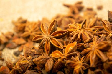 Çuval bezinin arka planında kabataslak desenli bir yıldız anason yığını. Kapat.