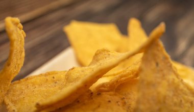 Tahta arka planda peynir soslu mısır cipsi. Kapat.