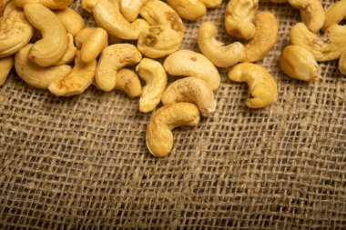 Çuval bezinde kabataslak desenli kaju fıstığı yığını. Kapat.