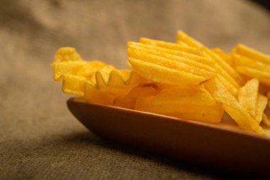 Tahta arka planda peynir soslu patates cipsi. Kapat.