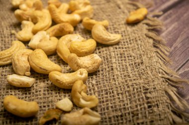 Çuval bezinde kabataslak desenli kaju fıstığı yığını. Kapat.