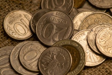 Kabataslak desenli kumaşın arka planında birkaç eski sikke. Kapat.