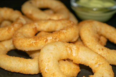 Soğan halkaları ve soslu cam tencere. Kapat.