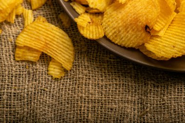 Kabataslak desenli ev yapımı kumaşın arka planında flüt patates cipsi. Kapat.