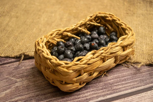 stock image Blueberry in a wicker basket on a background of homespun fabric with a rough texture. Close up