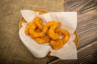 Hasır sepetteki beyaz kağıt peçetede hamurda kızartılmış Atlantik karidesleri. Kapat.