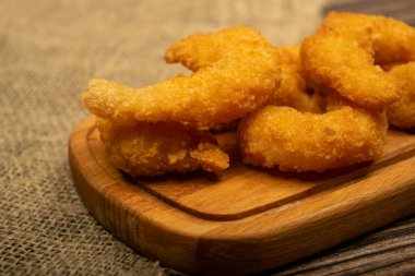 Tahta servis tahtasının üzerinde kızartılmış Atlantik karidesleri. Kapat.