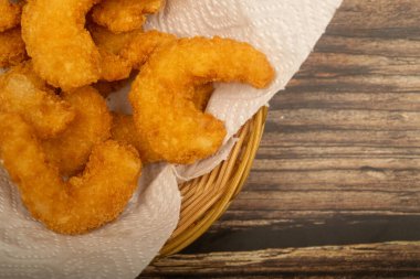 Hasır sepetteki beyaz kağıt peçetede hamurda kızartılmış Atlantik karidesleri. Kapat.