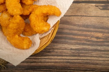 Hasır sepetteki beyaz kağıt peçetede hamurda kızartılmış Atlantik karidesleri. Kapat.