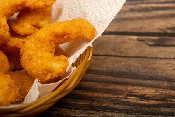 Hasır sepetteki beyaz kağıt peçetede hamurda kızartılmış Atlantik karidesleri. Kapat.