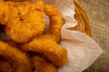 Hasır sepetteki beyaz kağıt peçetede hamurda kızartılmış Atlantik karidesleri. Kapat.