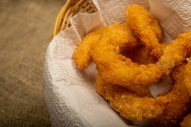 Hasır sepetteki beyaz kağıt peçetede hamurda kızartılmış Atlantik karidesleri. Kapat.