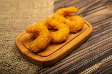 Tahta servis tahtasının üzerinde kızartılmış Atlantik karidesleri. Kapat.