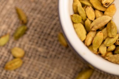 Seramik havanda kakule ve kabarık bir çuval bezinin arka planında kakule. Yakın plan, seçici odaklanma.