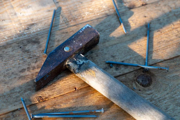 Old vintage hammer and nails on a wooden background, close-up, selective focus