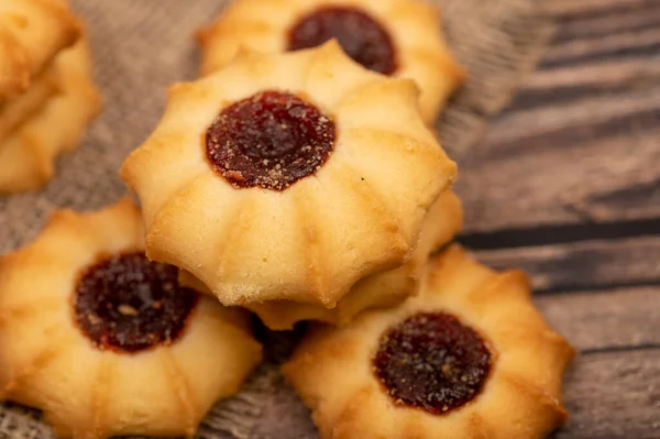 Homemade pastry cookies with jam on a background of homespun fabric with a rough texture, close-up, selective focus