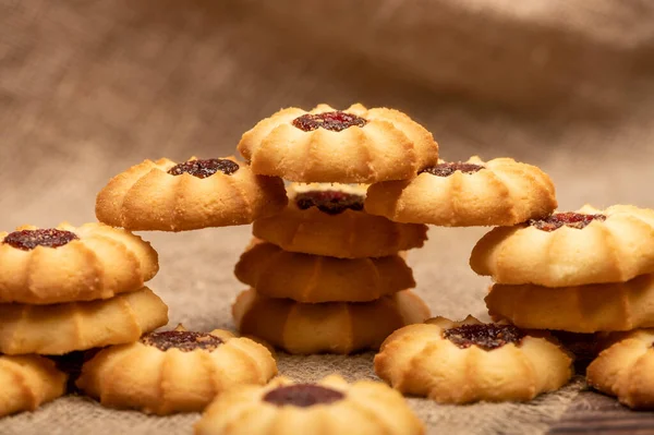 Homemade pastry cookies with jam on a background of homespun fabric with a rough texture, close-up, selective focus