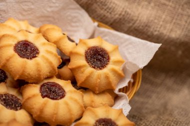 Hasır sepetin içinde reçelli ev yapımı kurabiyeler kabataslak desenli, yakın plan, seçici odaklı ev yapımı kumaş.