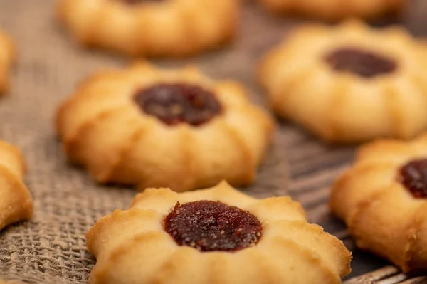 Homemade pastry cookies with jam on a background of homespun fabric with a rough texture, close-up, selective focus