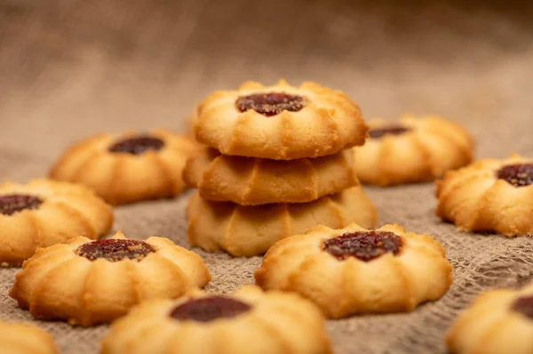 Homemade pastry cookies with jam on a background of homespun fabric with a rough texture, close-up, selective focus