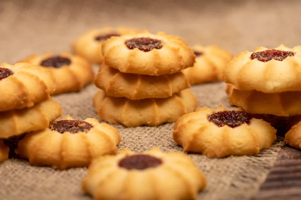 Homemade pastry cookies with jam on a background of homespun fabric with a rough texture, close-up, selective focus