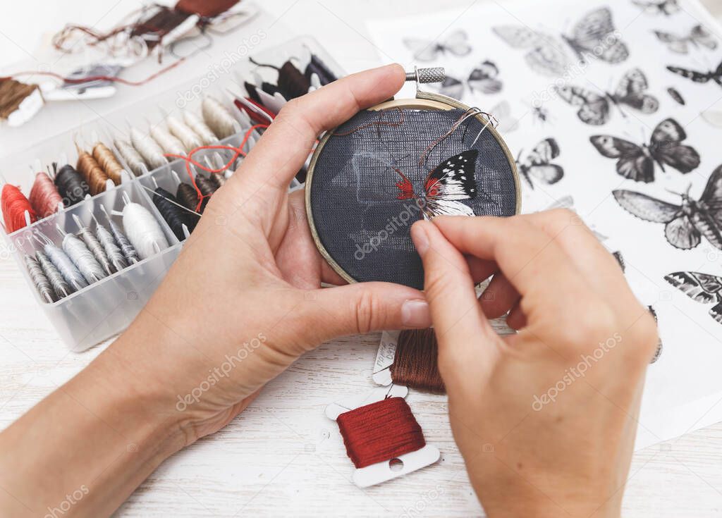 Woman embroider a butterfly. Process of making handmade embroidery. Hobby. Sewing tools. Remote home work.