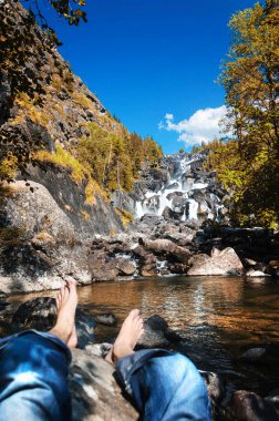 A man resting at Uchar waterfall in Altai mountains, Altai Republic, Siberia, Russia clipart