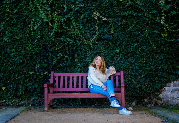 girl bench with wall of leaves