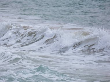 büyük dalgalar kum ve sahil kayalara çarpıyor