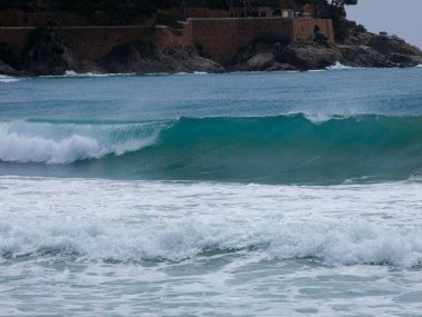 büyük dalgalar kum ve sahil kayalara çarpıyor