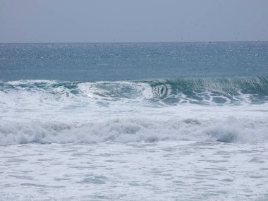 büyük dalgalar kum ve sahil kayalara çarpıyor