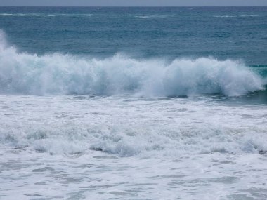 büyük dalgalar kum ve sahil kayalara çarpıyor