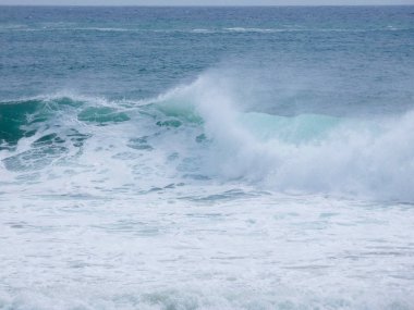 büyük dalgalar kum ve sahil kayalara çarpıyor