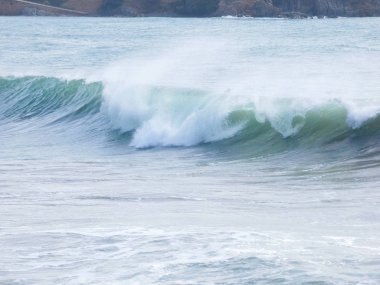 büyük dalgalar kum ve sahil kayalara çarpıyor
