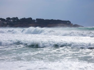 büyük dalgalar kum ve sahil kayalara çarpıyor