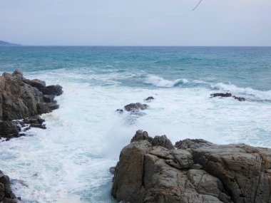 büyük dalgalar kum ve sahil kayalara çarpıyor